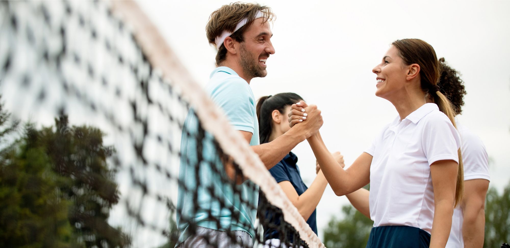 Four tennis players shaking hands after finishing a game. 