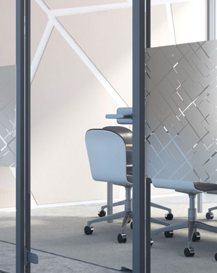 Office meeting room with glass walls covered in geometric frosted film patterns, with chairs and tables visible behind the semi‑opaque design. 