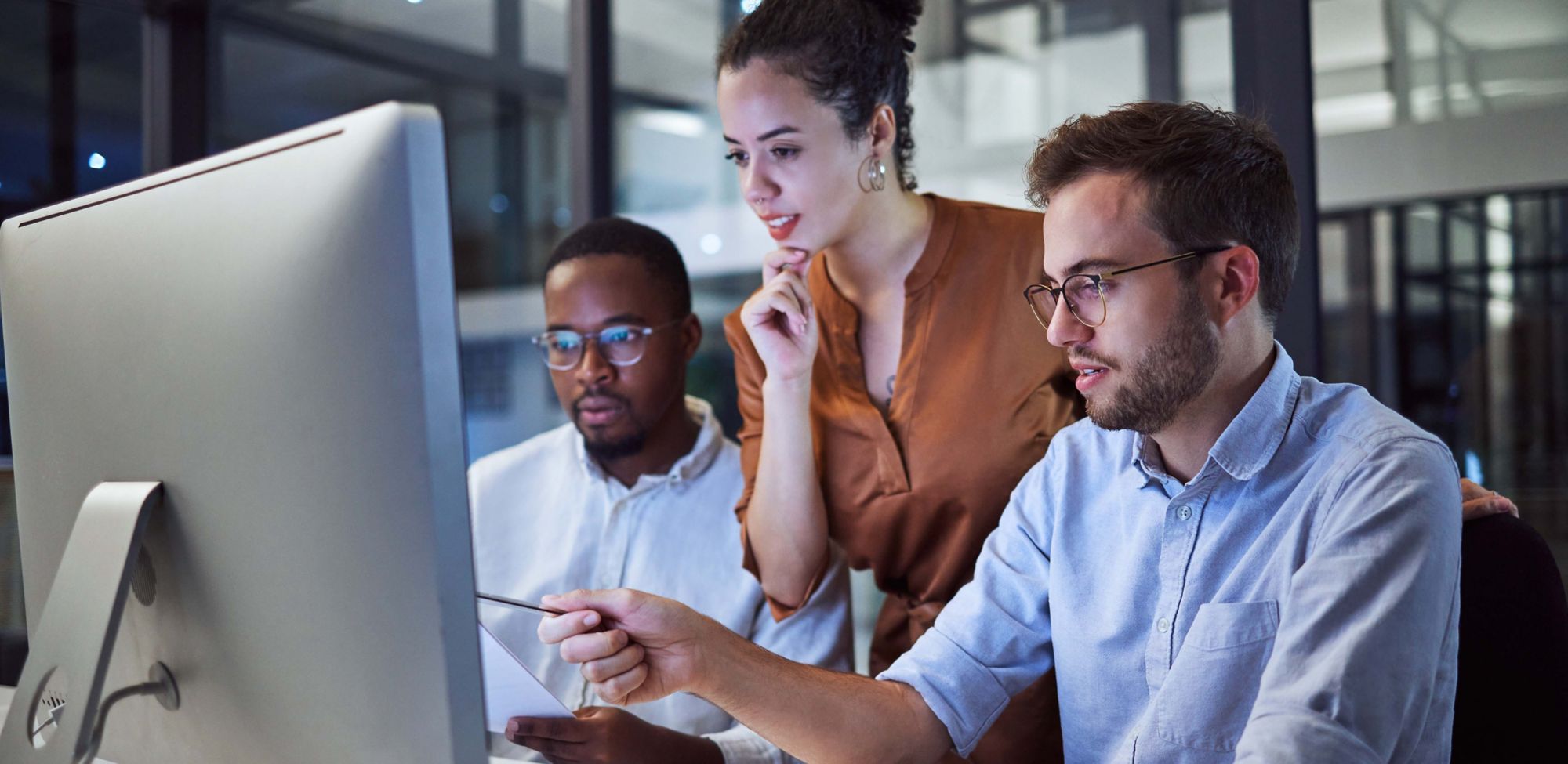 Three employees discussing information presented on a computer screen. 