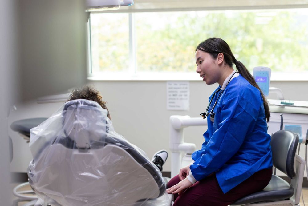  Tinah Le talks to a patient in the dental chair.   