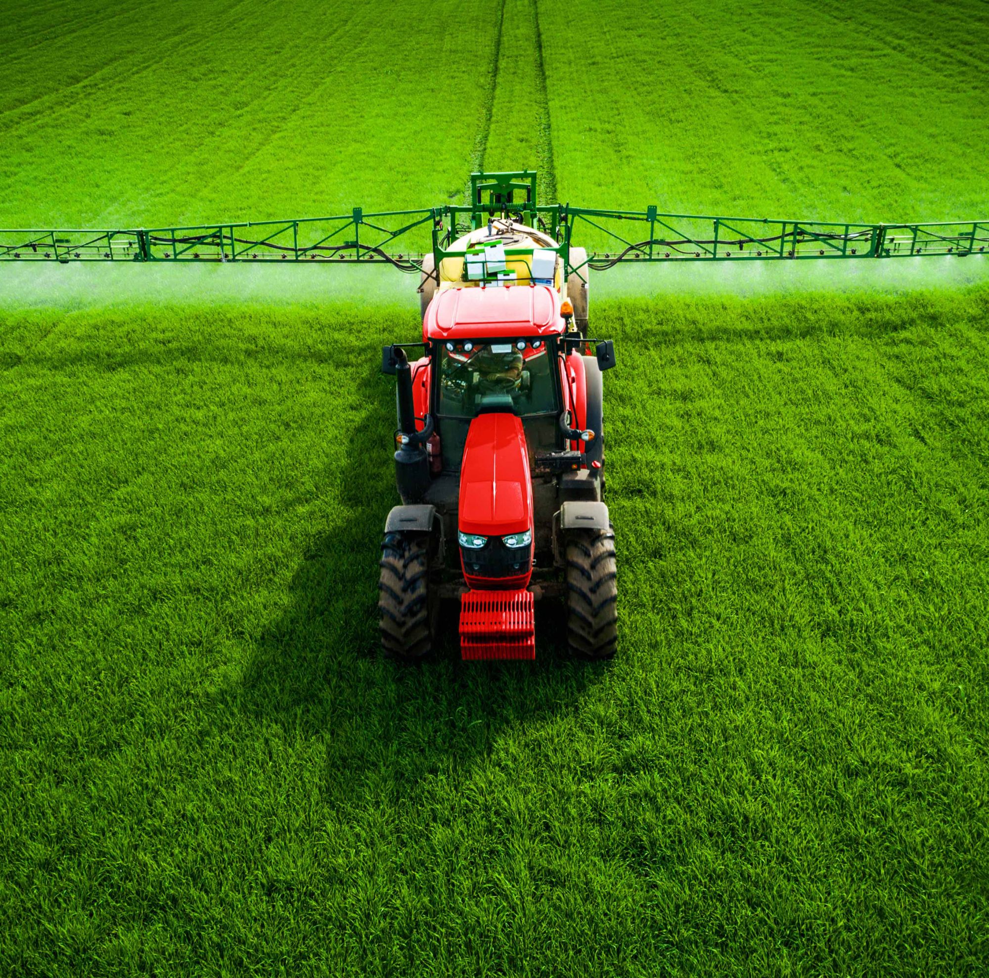A tractor spraying product on a green field. 