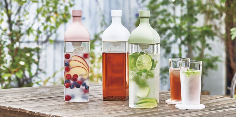 HARIO pitcher is filled with lime and mint water with two drinking glasses beside it. 