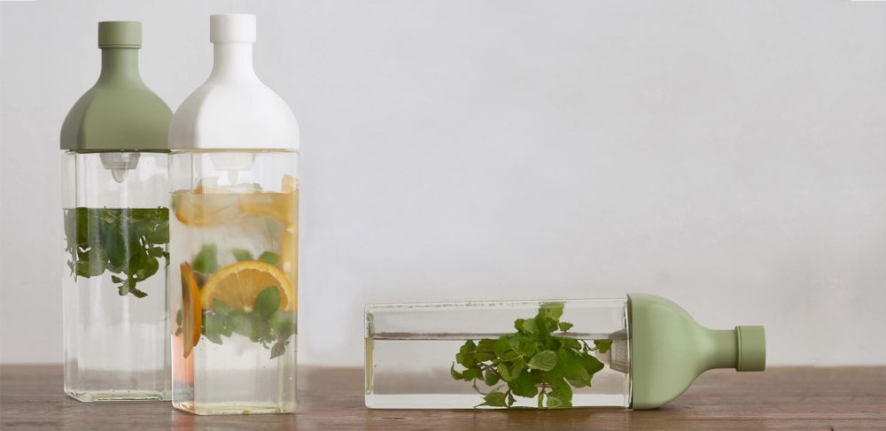 Two pitchers stand upright, while one lays horizontally. All are filled with infused water.