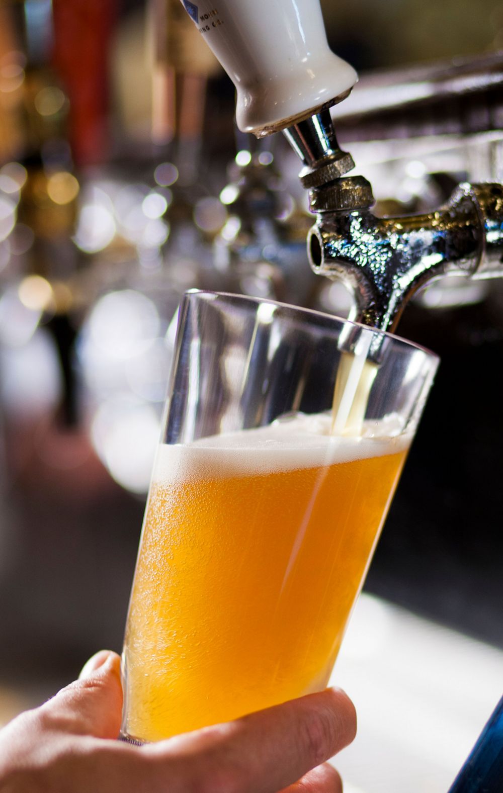 A person fills up a cup made from Tritan with beer from a tap. 