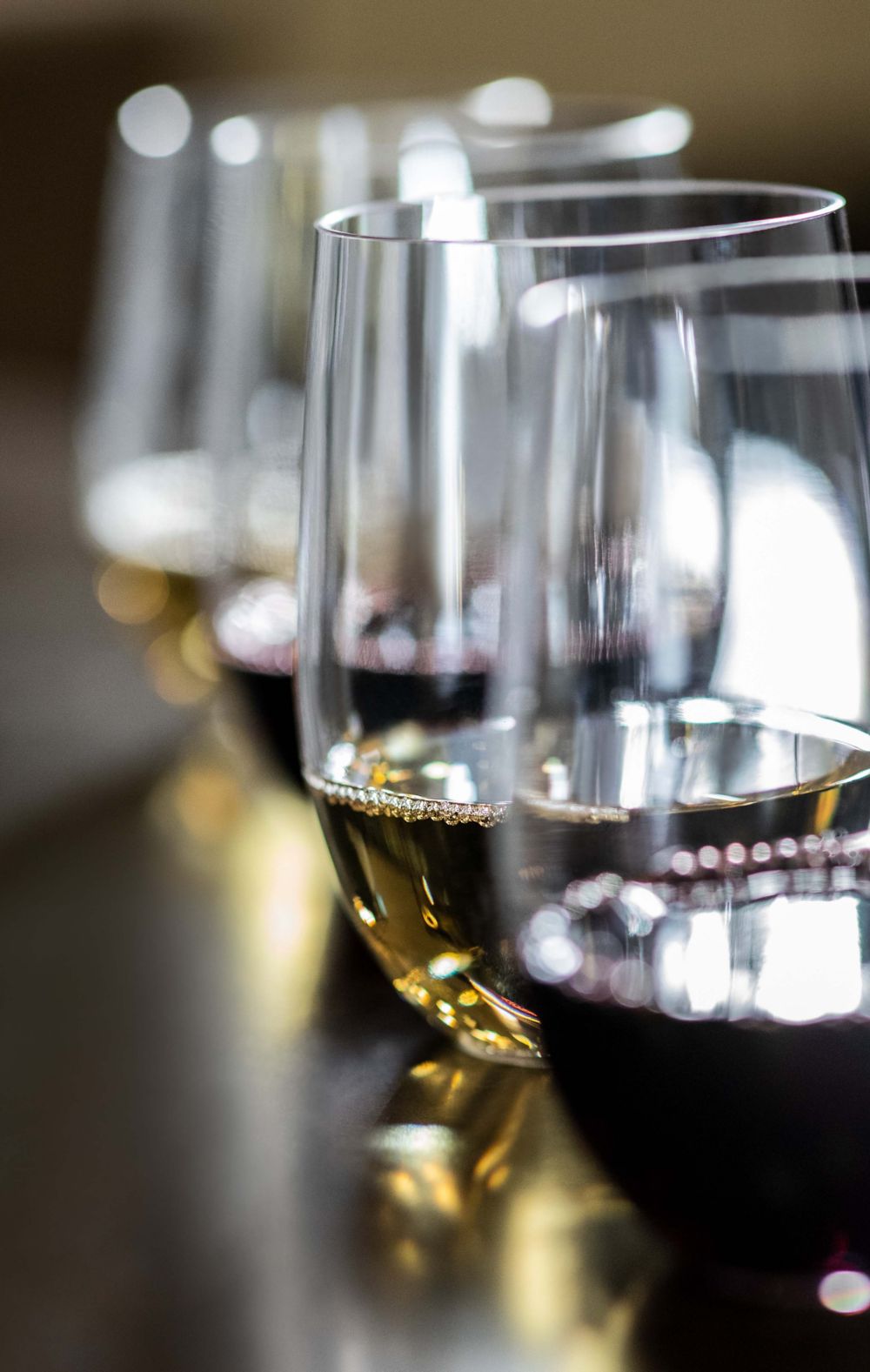 A row of wine glasses on a glossy surface. 