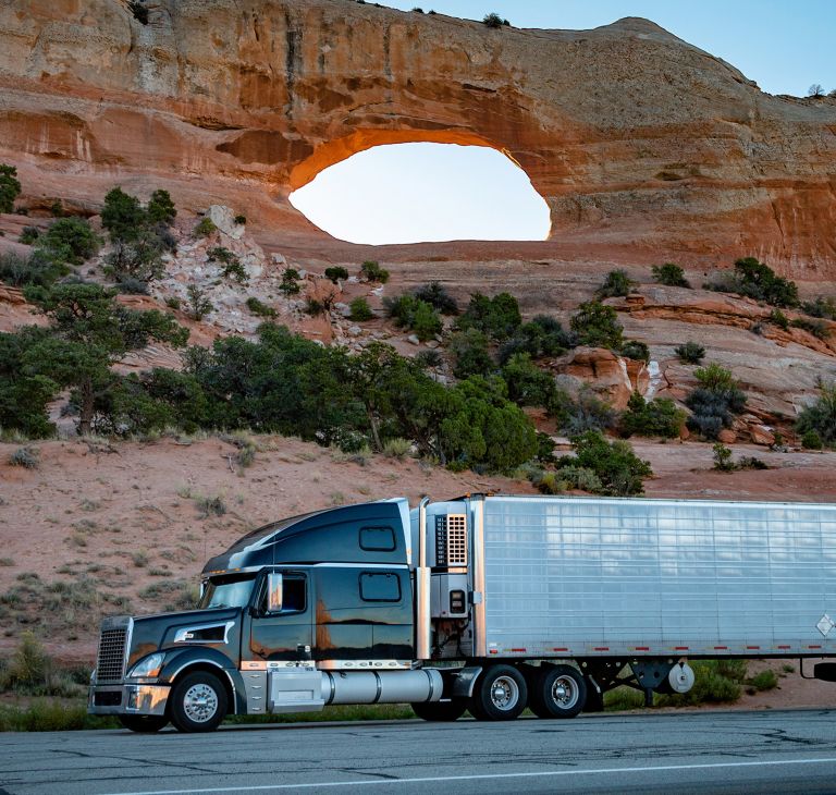 A semitruck drives through the dessert. 