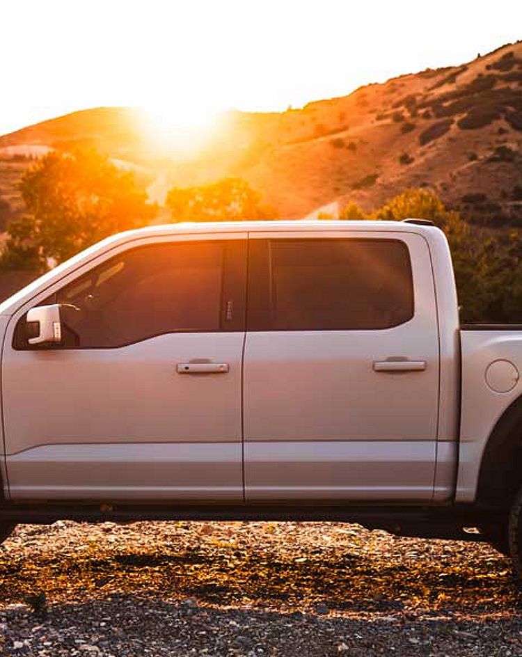 Truck in an offroad setting with a sunrise behind 