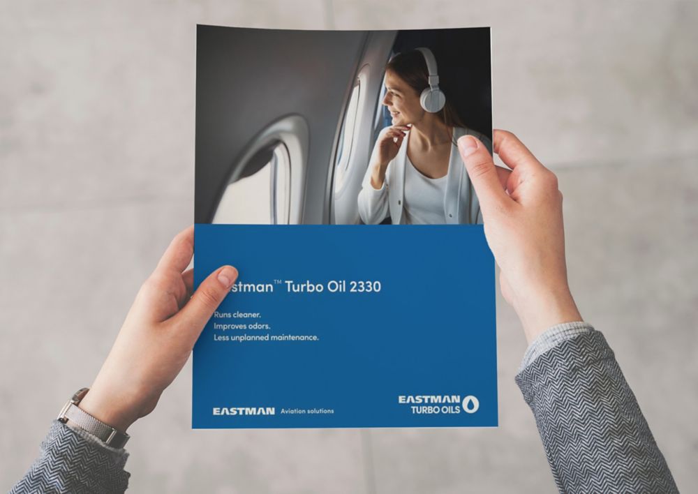 A person holds an Eastman Turbo Oil 2330 brochure.  