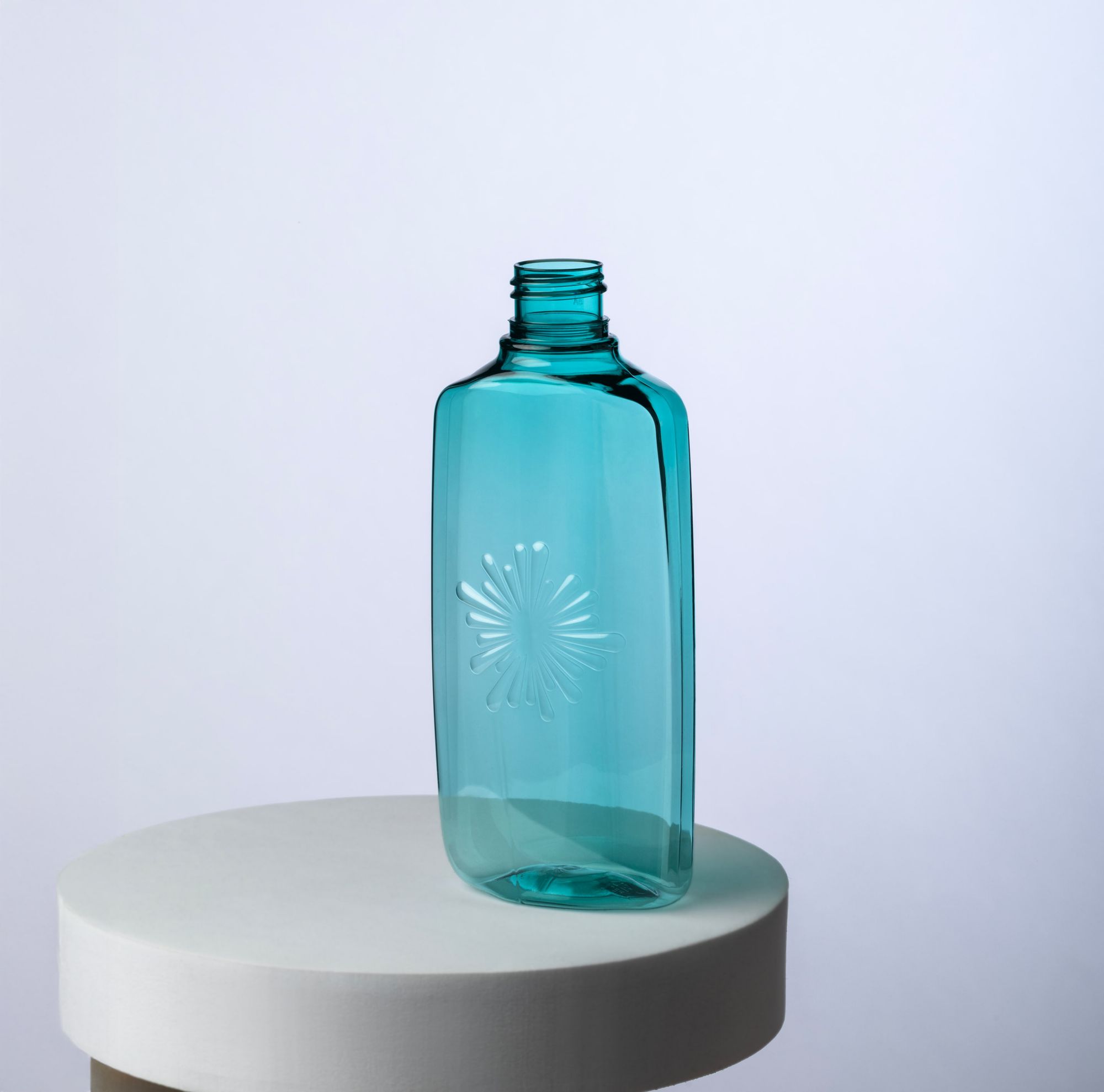 Turquoise cosmetic bottle made from Cristal Renew EN series displayed on a round white stand. 