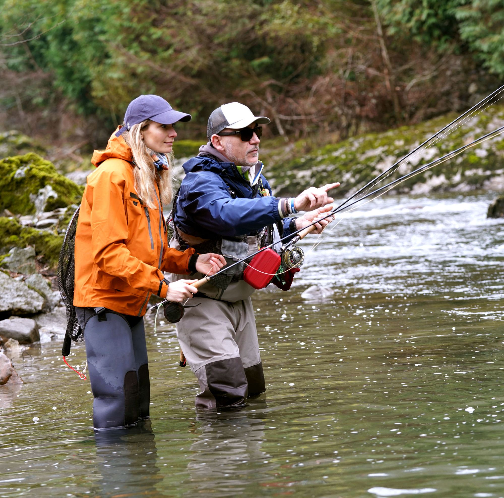 Two people stand in a river and fly fish. 