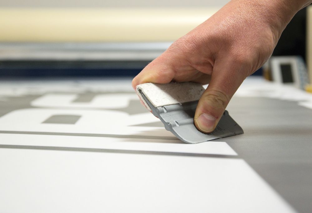A person presses down a vinyl decal. 