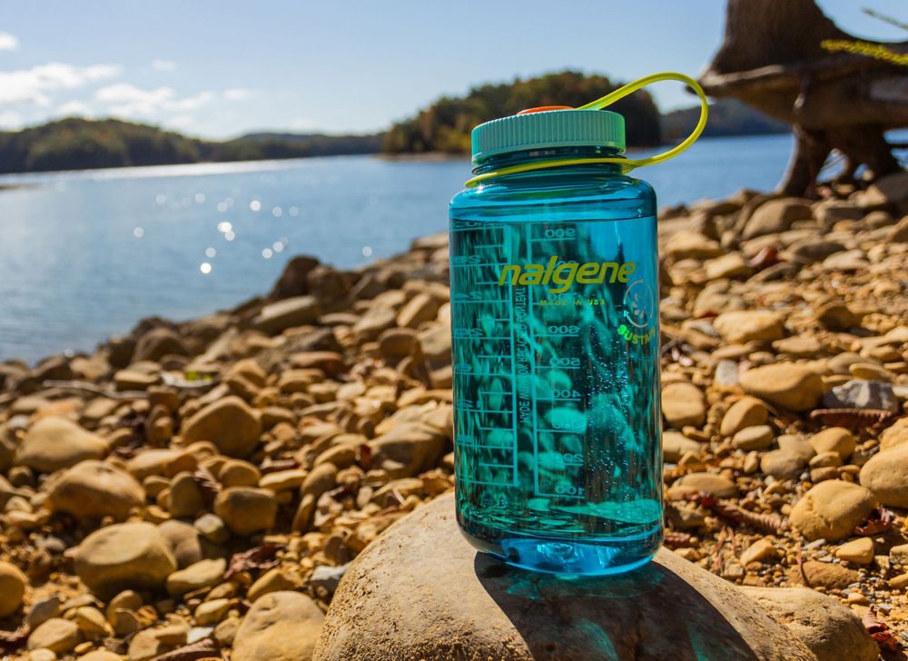 Nalgene water bottle on rocks by lake. 