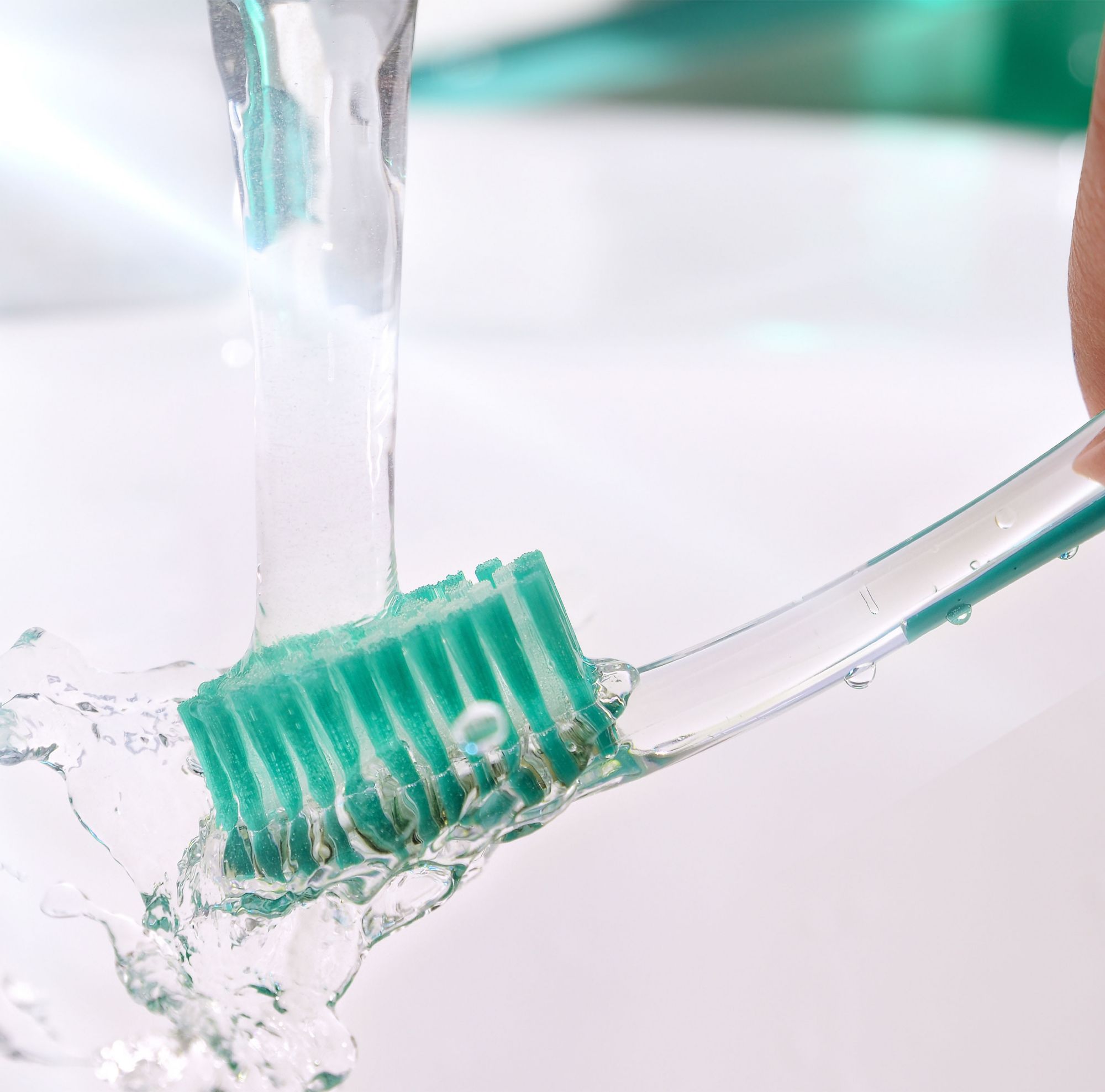 A toothbrush being rinsed under running water. 