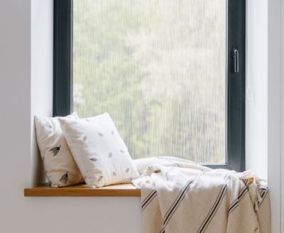 Cozy, private window nook showing the installed Waterfall film behind throw pillows.