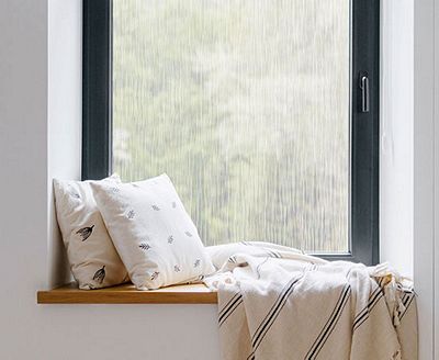 Cozy, private window nook showing the installed Waterfall film behind throw pillows.