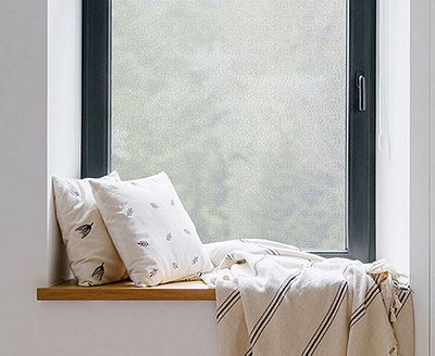 Cozy, private window nook showing the installed Winter Morning film behind throw pillows.