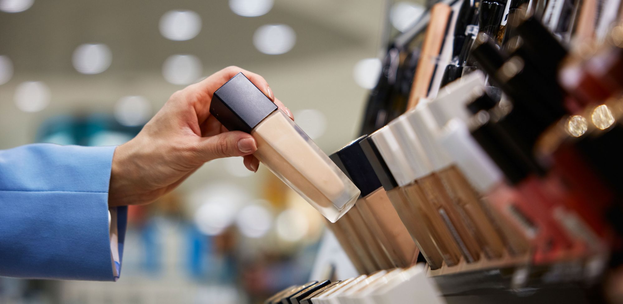 A liquid foundation bottle is picked up from a retail shelf.   
