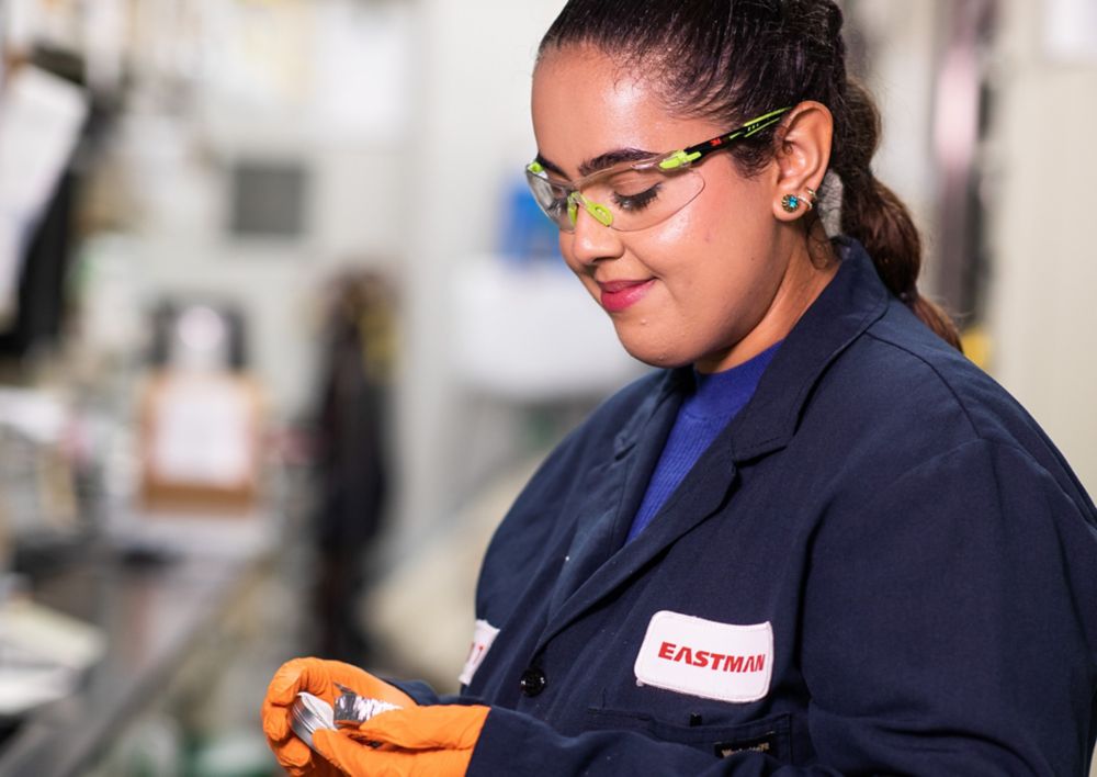Un empleado de Eastman inspeccionando un producto mientras usa gafas de protección. 