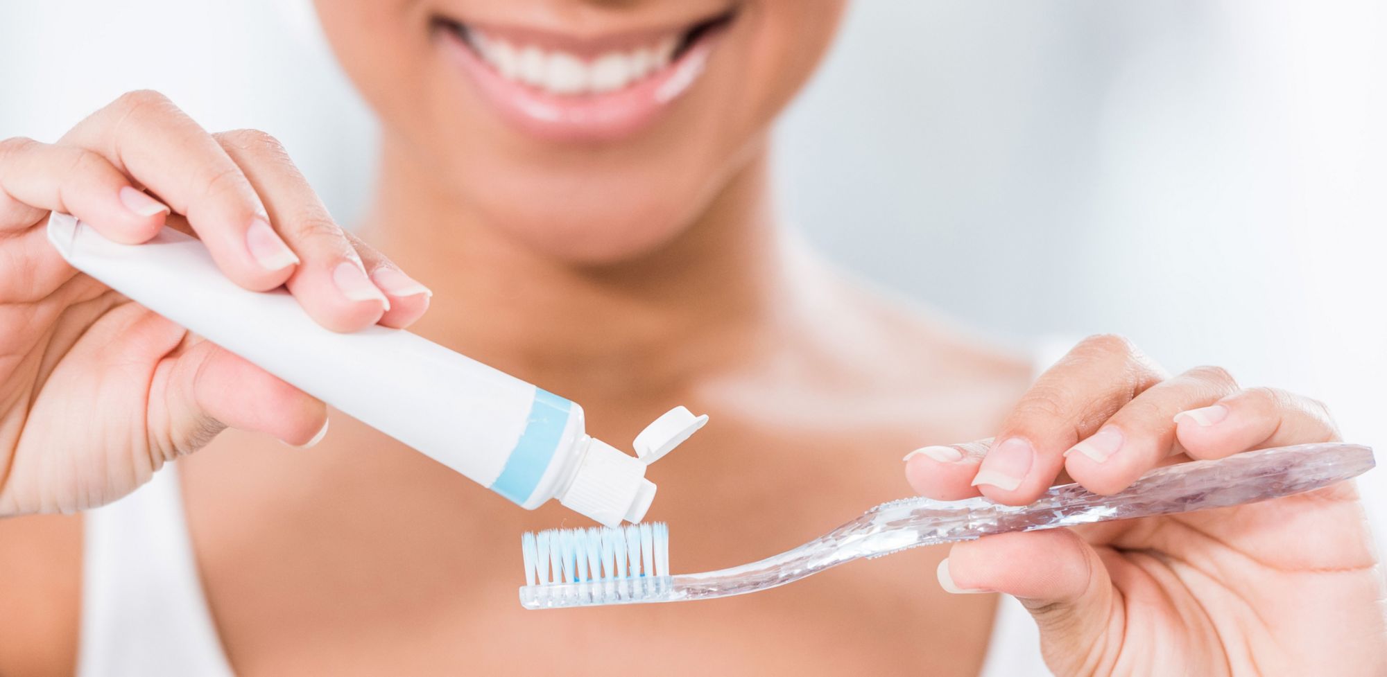 A person applying toothpaste to a toothbrush.  