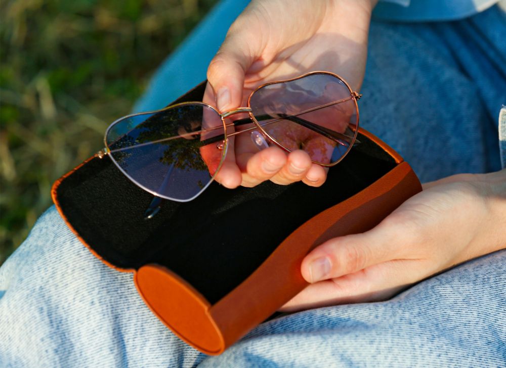A person taking out heart-shaped wire glasses from their case. 