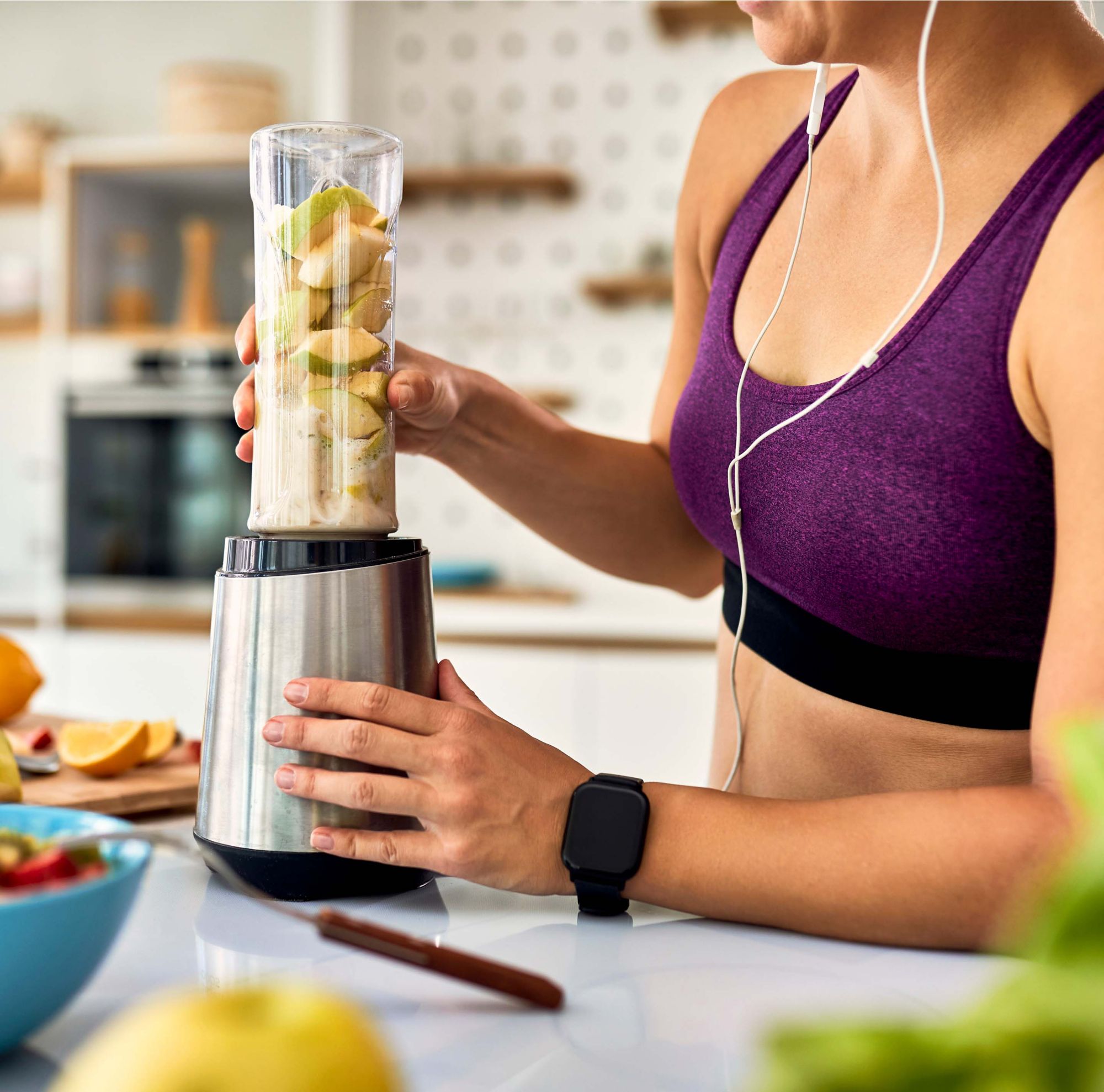 A woman using a blender in a kitchen. 
