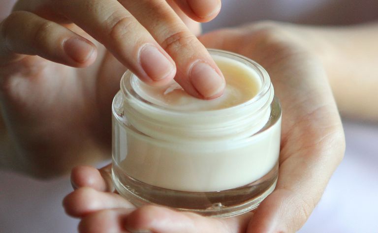 Fingers dip into a jar of hand cream. 