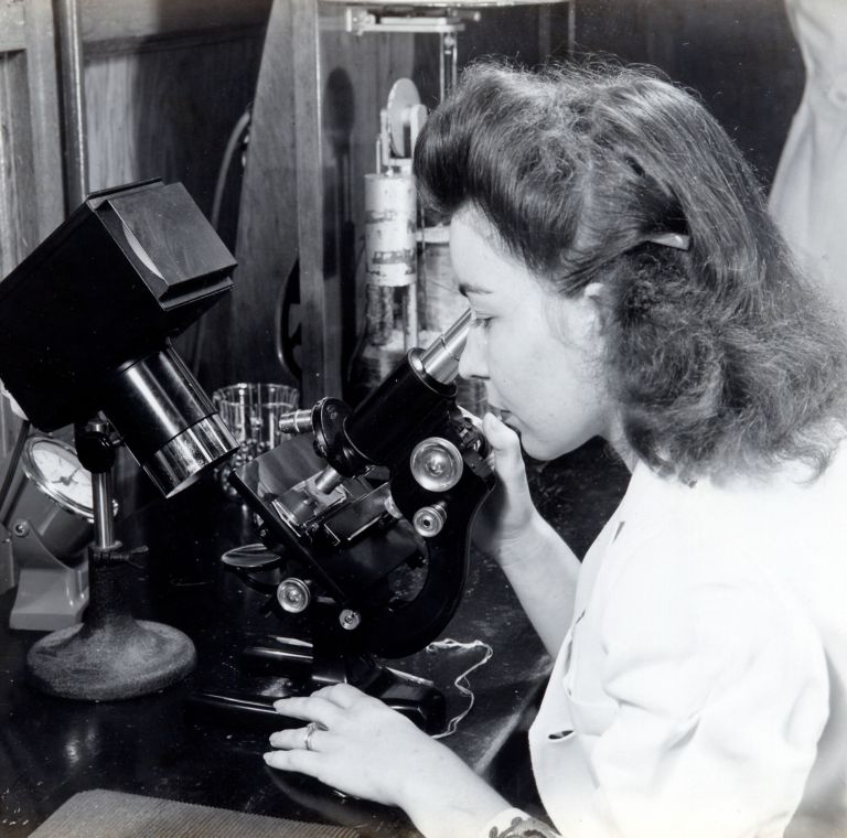 A woman looks into a microscope. 