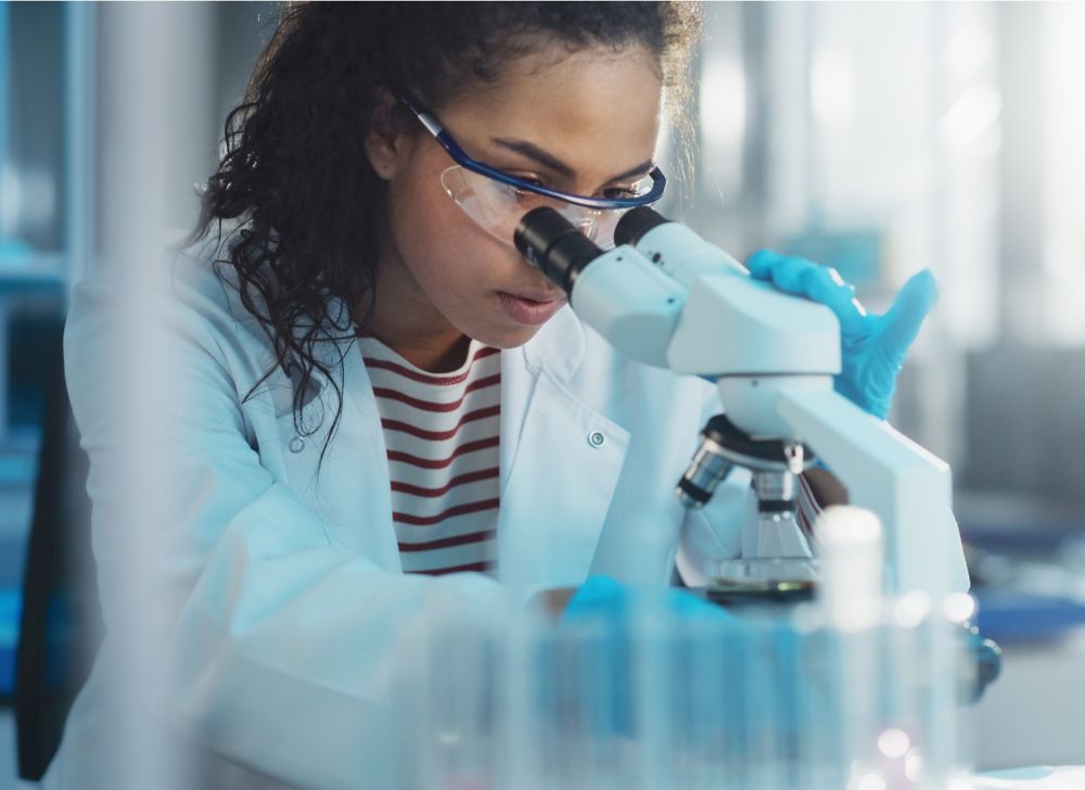 Eastman engineer is doing a chemical test using a microscope in a lab. 