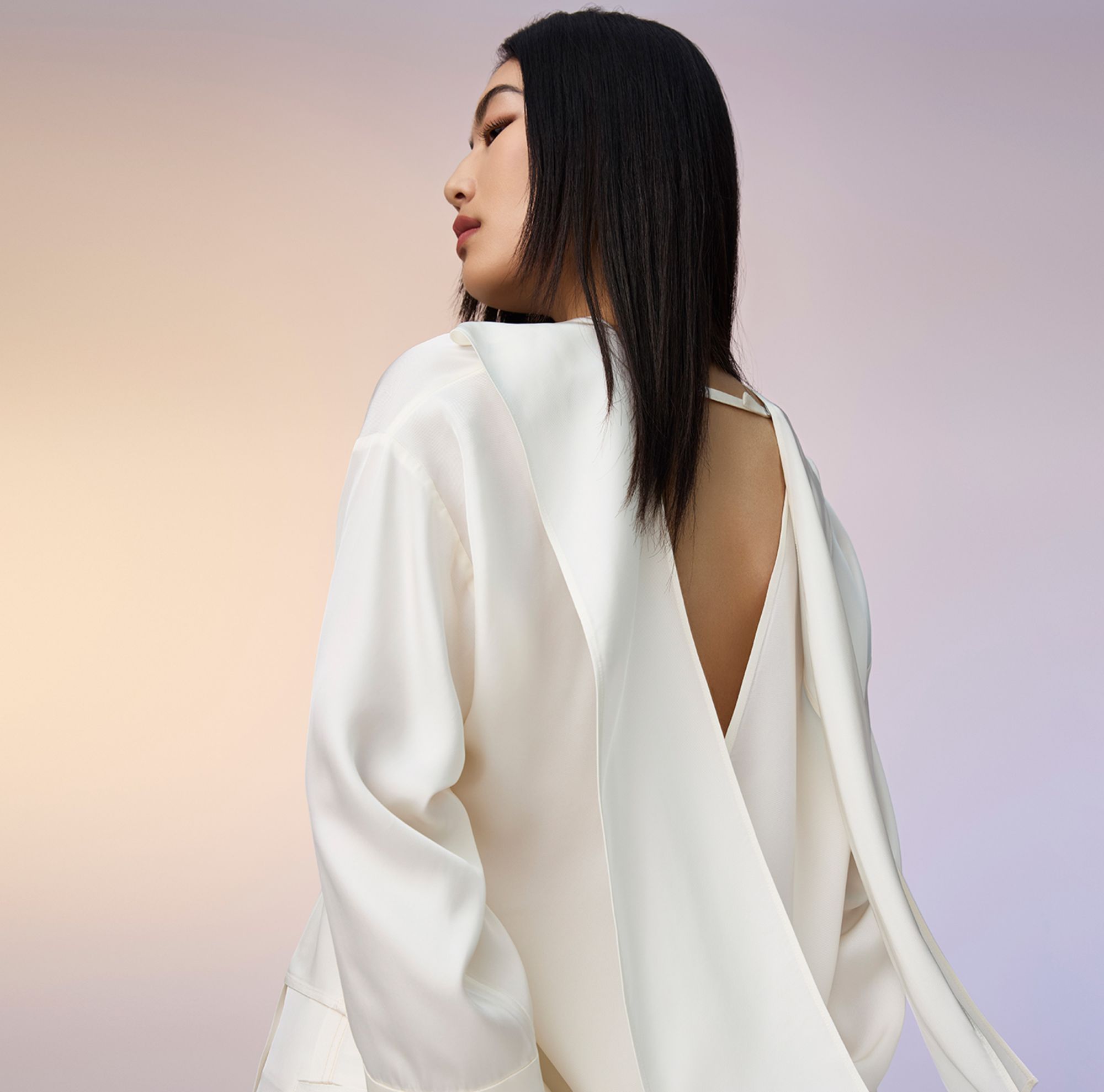 A woman wearing a white blazer and tailored pants. 