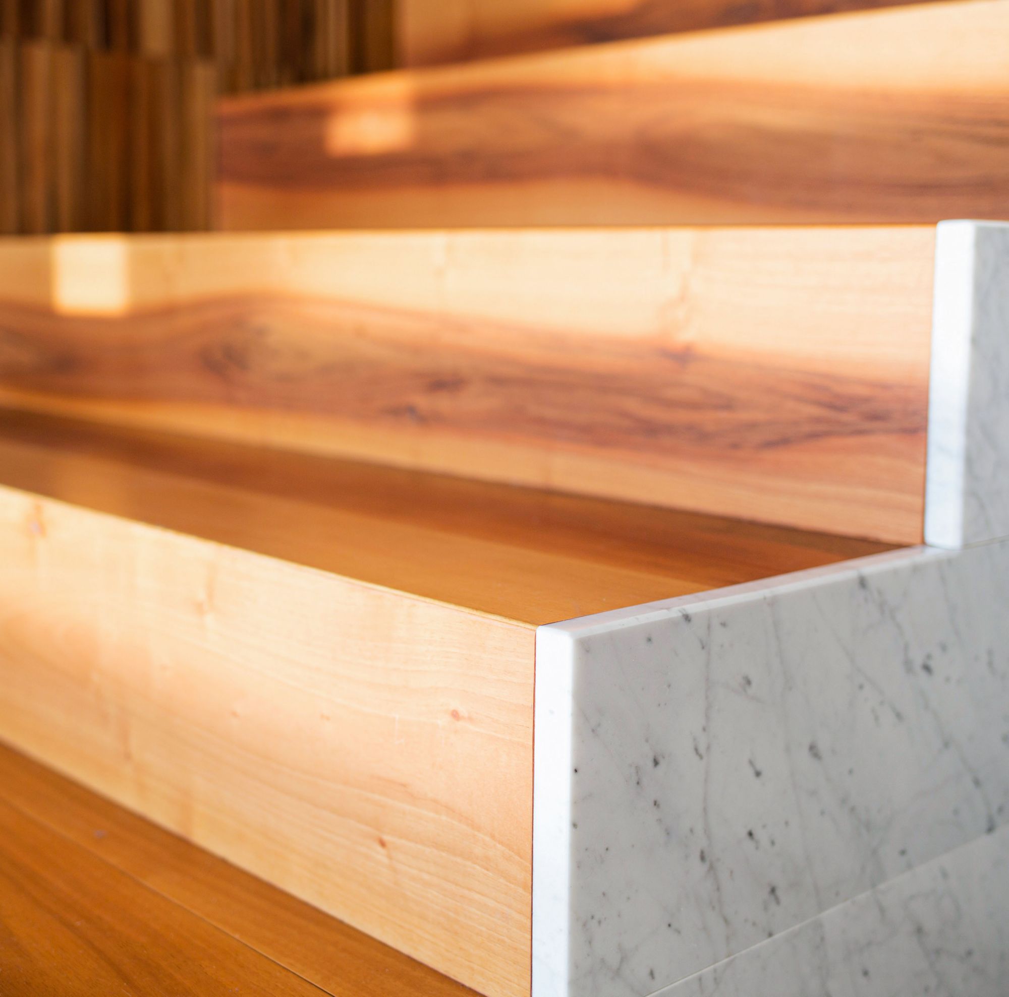 A close-up of a wood staircase with marble on the side. 