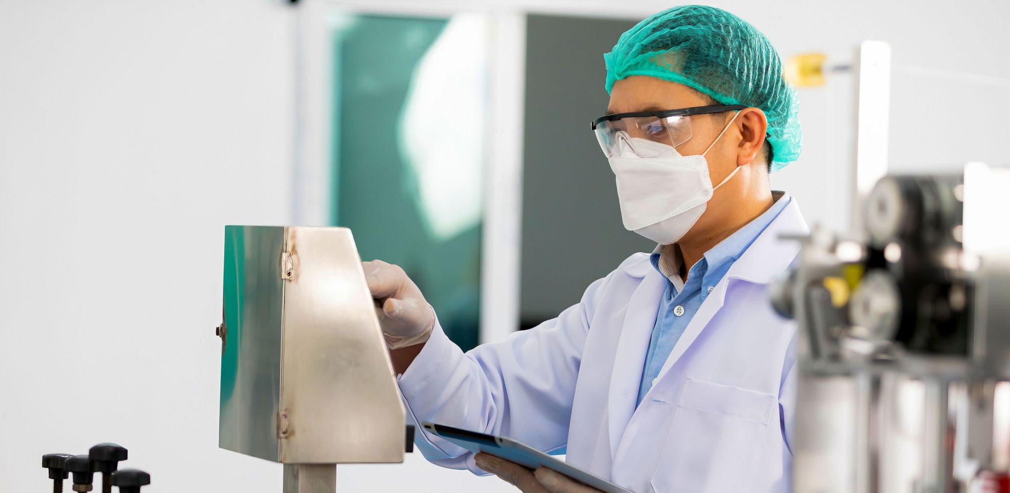 A worker in PPE checking a machine panel. 