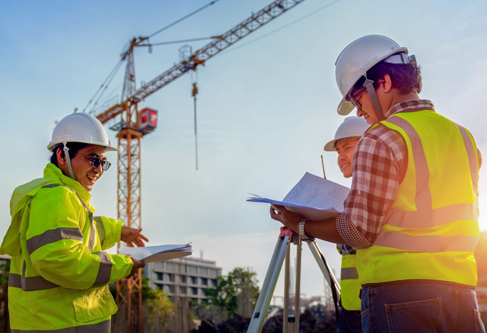 Engineers in PPE at a construction site discussing project progress 