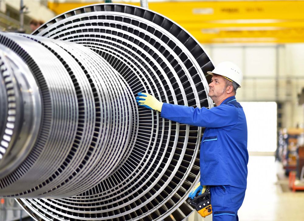 A man looks over materials at a steam turbine manufacturing plant.  