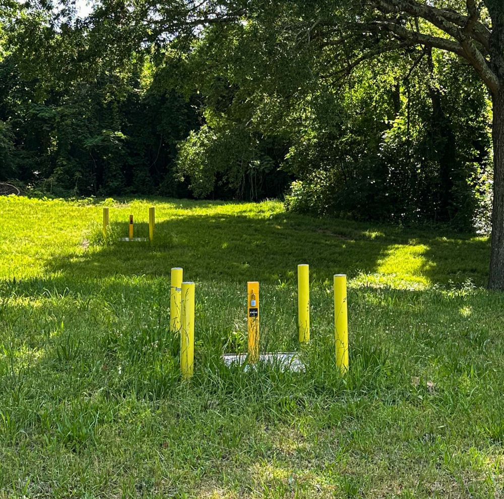 Underground utility markers are visible in a grassy field.  