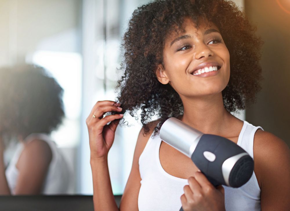 A person dries their hair with a hair dryer.   